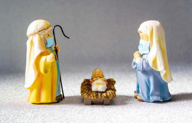 Figures of Saint Joseph, the Virgin Mary and the newborn baby Jesus with hygienic masks. Christmas with the Covid-19 pandemic stock photo