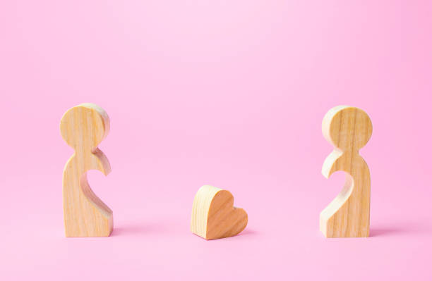 figurines of people separated from each other and a lost heart. breakup, end of love. relationship problems of the couple. take the first step towards reconciliation. not whole without each other - lost first imagens e fotografias de stock
