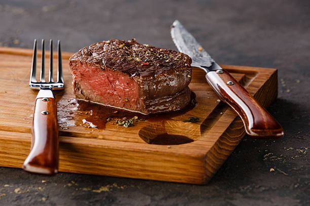 Filet Mignon Steak on wooden board Filet Mignon Steak on wooden board on black background cut of meat stock pictures, royalty-free photos & images