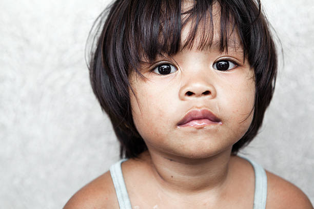 Filipina girl portrait Portrait of an adorable, impoverished girl from the Philippines against wall. philippines girl stock pictures, royalty-free photos & images