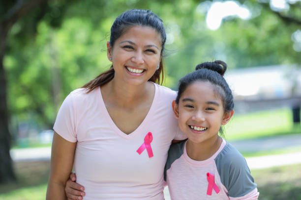 Filipino mother and daughter wearing breast cancer awareness pink ribbons Filipino American mother and daughter are smiling and looking at the camera. Parent and child are wearing pink breast cancer awareness ribbons. filipino family stock pictures, royalty-free photos & images