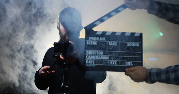 Film crew shooting take of scene in studio Cameraman using shooting equipment on tripod while recording take of scene working in team clapboard photos stock pictures, royalty-free photos & images