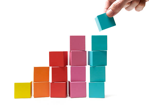 Final touch to achievement Putting the final building block onto the top of a rising pile signifying success and achievement. toy block stock pictures, royalty-free photos & images