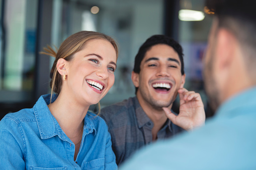 Financial advisor discussing business with couple. Couple are casually dressed. They sitting in an office and looking very happy smiling and laughing