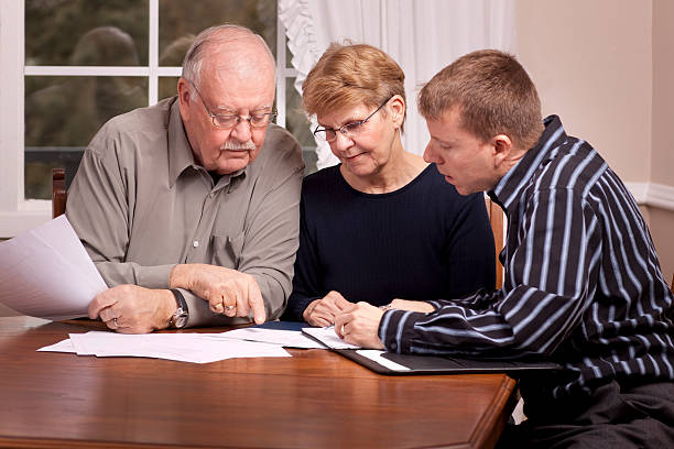 Financial advisor with senior couple going over paperwork stock photo