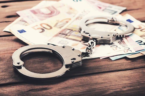 financial crime concept - money and handcuffs on the table financial crime concept - money and handcuffs on the table money laundering stock pictures, royalty-free photos & images