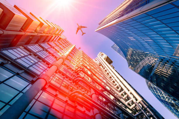 Financial district in central London and passing airplane above with sun flare and light rays - creative stock image stock photo