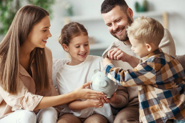 financiële planning familie moeder vader en kinderen met spaarvarken thuis - sparen stockfoto's en -beelden