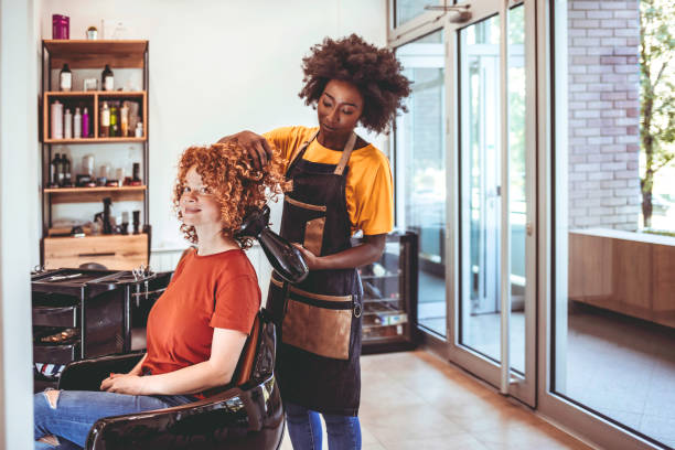 Finding that perfect hair-do African Hairdresser drying woman's hair with hair dryer in beauty salon. beauty spa stock pictures, royalty-free photos & images