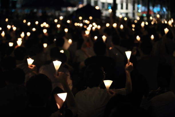finding the light in dark. a haza candlelight vigil find each other in darkness, blur background in hong kong victoria park stock photo