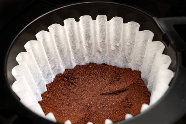 Fine grounded coffee in a white paper filter in a drip machine stock photo