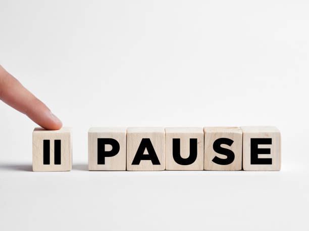 Finger presses the pause button on wooden cubes. stock photo