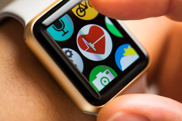 Close up shot pergelangan tangan wanita mengenakan jam tangan pintar. Ikon aplikasi track kesehatan menyentuh jari di layar sentuh.