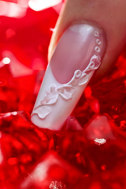 Finger with beautiful manicure touch a red crystal stock photo