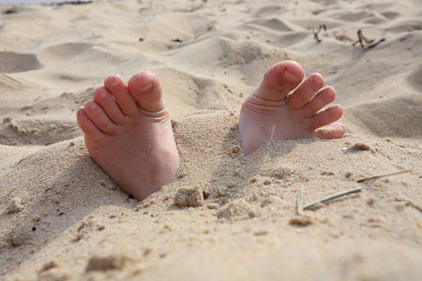 Fingers from sand Children's feet are buried in sand human feet buried in sand. summer beach stock pictures, royalty-free photos & images