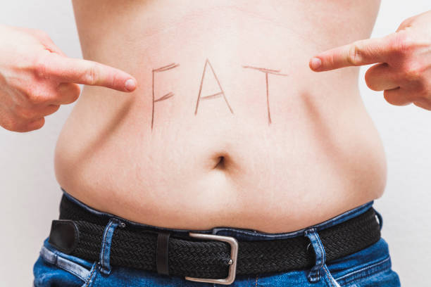 Fingers pointing word "fat" written in man's belly stock photo