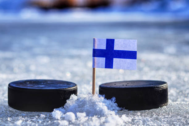 A Finland flag on toothpick between two hockey pucks stock photo