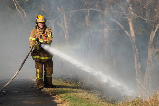 Fire fighter spraying water on a bush fire in an suburban area of Knox City in Melbourne east. stock photo