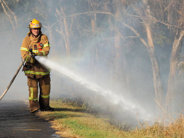 Fire fighter with a hose at a bush fire in an suburban area of Knox City in Melbourne east. stock photo