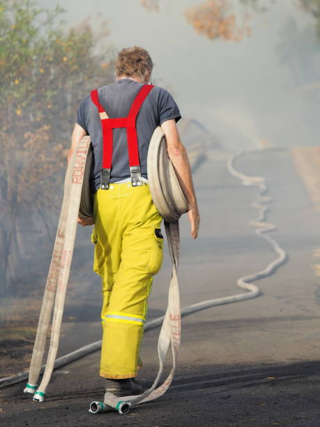 Fire fighter with rolls of fire hose at a bush fire in an suburban area of Knox City in Melbourne east. stock photo