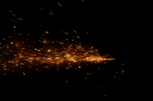Fire sparks on a black background during metal cutting
