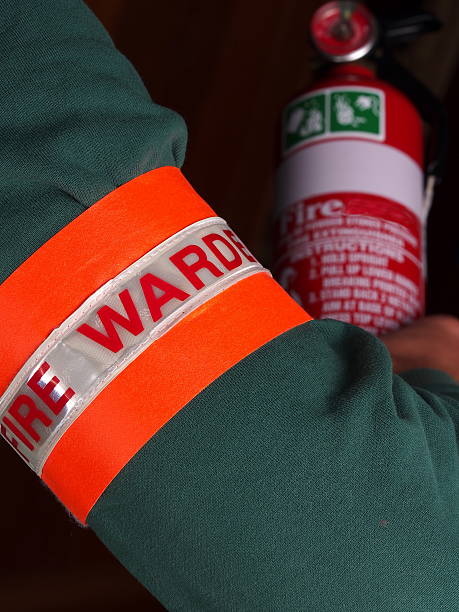 Fire warden with identification patch holding a fire extinguishe stock photo
