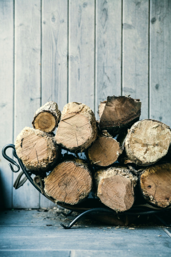Firewood stacked by a wooden background.