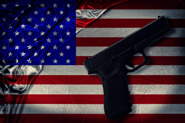Firearm disposed by diagonal on a United States of America flag Firearm disposed by diagonal on a United States of America flag. Directly above. nra stock pictures, royalty-free photos & images