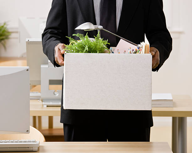 Fired businessman packing personal desk items in box stock photo