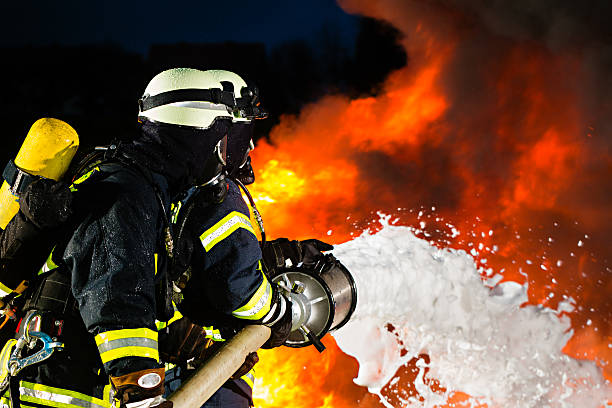 bombero de bomberos de extinción un gran blaze - firefighters fotografías e imágenes de stock