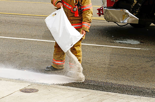 Firefighter pouring absorb any on oil spilled from a wreck stock photo
