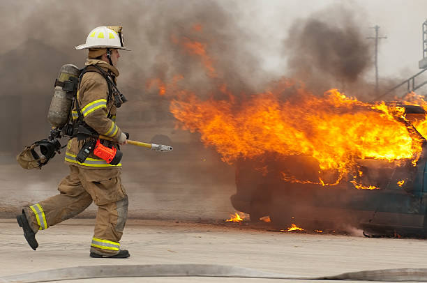 Firefighter running toward burning building stock photo