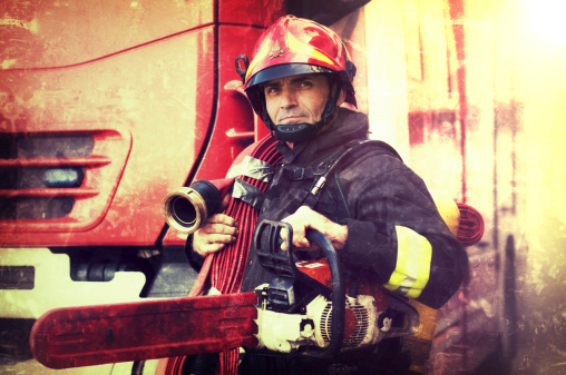 Firefighter with chainsaw and fire hose in the Wings. Grunge effects added.