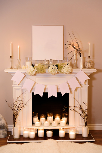 Fireplace decorated for Easter. A view on a fair white fireplace in warm candlelight making an Easter atmosphere with decorations. Place for text.