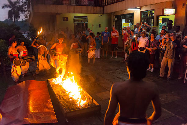Firewalking in front of Sacred Tooth Relic Temple Kandy, Sri Lanka - February 26, 2015: A night performance in front of the temple, yung man with bare chest is performing firewalking, behing him two man play drums, large group of spectaters around the scene watching and taking photos.  firewalking stock pictures, royalty-free photos & images