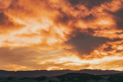 Firey orange and red cloudy sky over desert mountain range