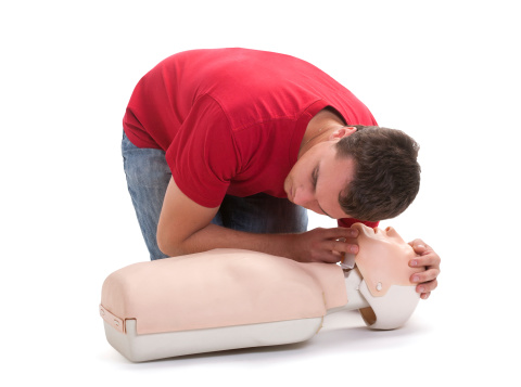 Man in red top performing first aid on a cpr dummy - check breathing cpr.