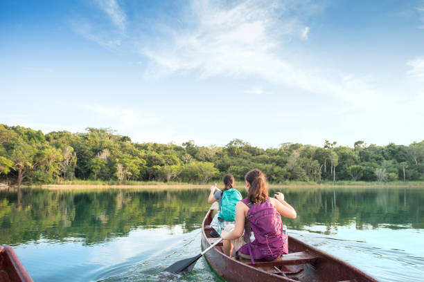 First Person Perspective of Sisters with Backpacks Canoeing in Lake POV of Eurasian sisters paddling in Punta Laguna Nature Reserve, Tulum, Yucatan Peninsula, Quintana Roo, Mexico eco tourism stock pictures, royalty-free photos & images