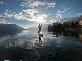 First person point of view of a woman paddling on a stand up paddle board on a lake at sunset