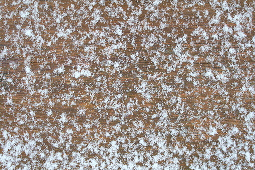 First snow on a wooden board. Background. Texture.