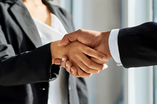 Shot of a businessman and businesswoman shaking hands in a modern office