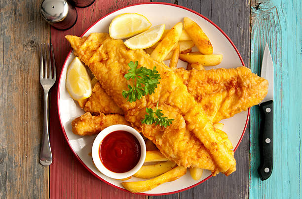 Fish and chips Close up of two pieces of battered fish on a plate with chips fried fish stock pictures, royalty-free photos & images