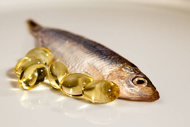 Fish oil capsules next to sprat Cod liver oil together with sprat. fish oil stock pictures, royalty-free photos & images
