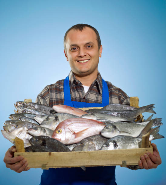 Fish Vendor Male fish vendor smiling with a box of fresh fish mullet haircut photos stock pictures, royalty-free photos & images