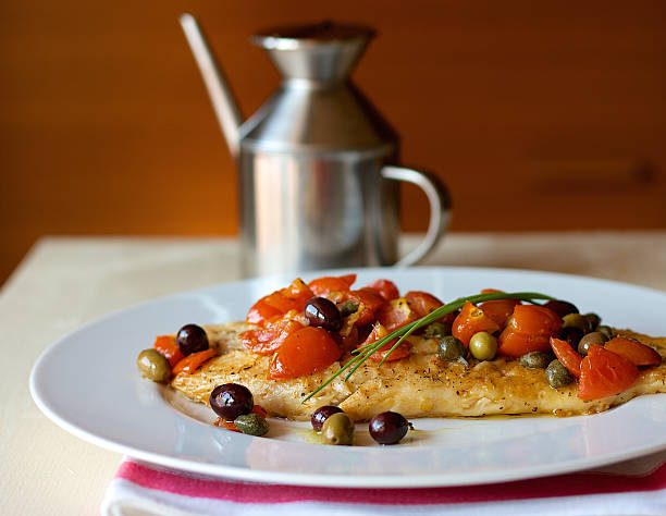 Fish with tomatoes and capers Italian traditional fish with tomatoes, olives and capers caper stock pictures, royalty-free photos & images