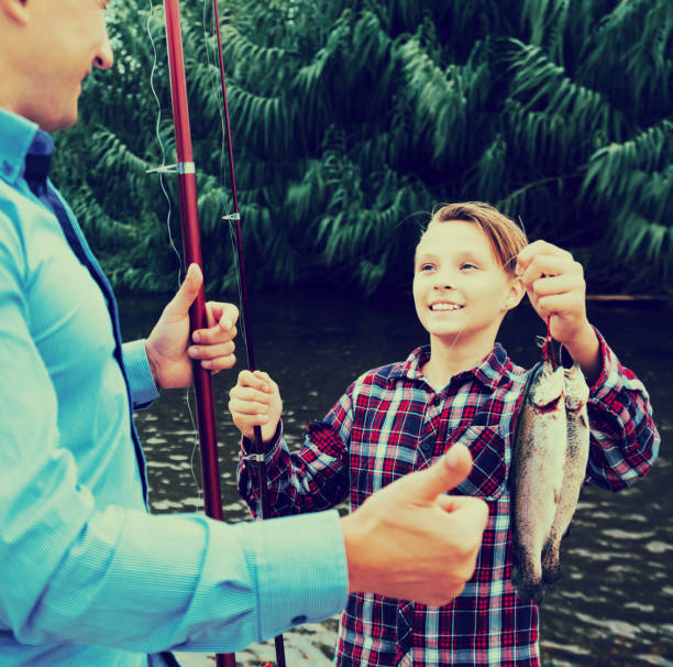 Fisher boy showing catch fish Smiling teenager boy showing his father catch fish he holding in hands white perch fish stock pictures, royalty-free photos & images