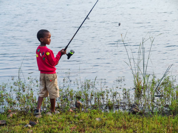 fisherman African kid catching a fish by the lake stock photo