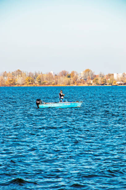 Fisherman in a motor boat on the river, autumn. stock photo