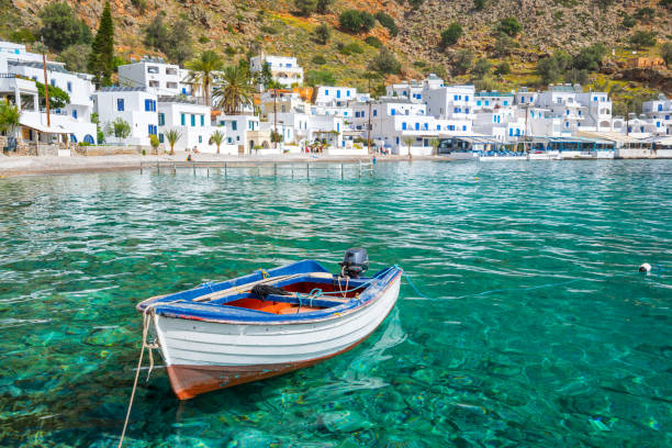 Fishing boat and the scenic village of Loutro in Crete, Greece Fishing boat and the scenic village of Loutro in Crete, Greece mediterranean sea stock pictures, royalty-free photos & images