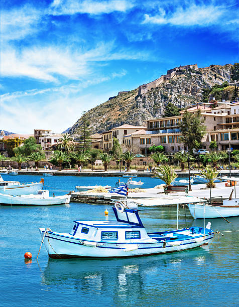 Fishing boat Traditional greek fishing boat with Palamidi castle in background in Nafplio, Greece. Stitched image. peloponnese stock pictures, royalty-free photos & images